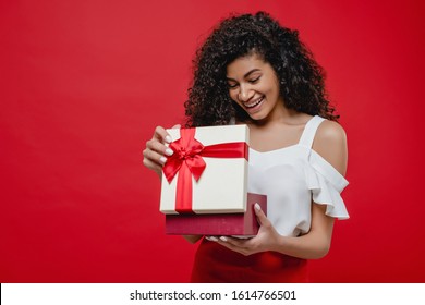 Beautiful Black Woman Opening Valentine Gift Box Isolated On Red Background