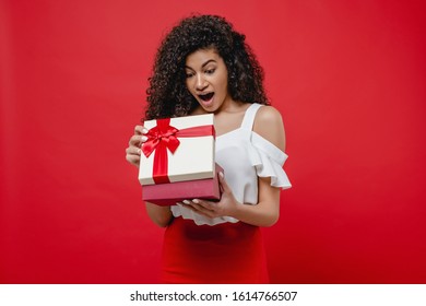 Beautiful Black Woman Opening Valentine Gift Box Isolated On Red Background