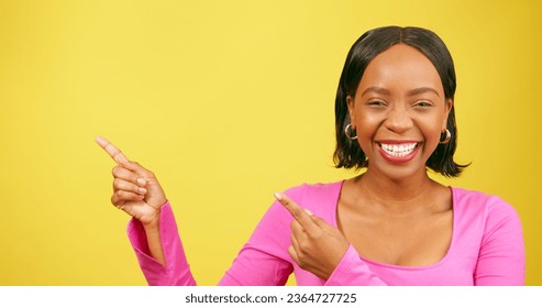 Beautiful Black woman pointing up at copy space, yellow studio background - Shutterstock ID 2364727725