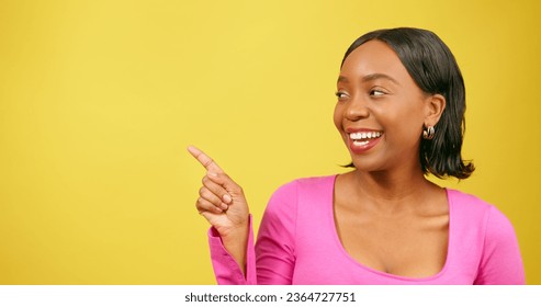 Beautiful Black woman pointing left at copy space, yellow studio background - Shutterstock ID 2364727751