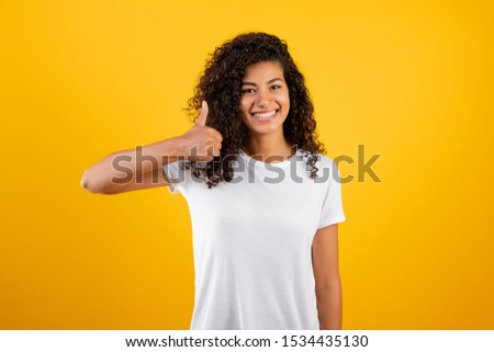 beautiful black woman showing thumbs up isolated over yellow