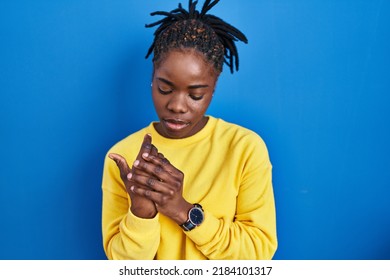 Beautiful Black Woman Standing Over Blue Background Suffering Pain On Hands And Fingers, Arthritis Inflammation 