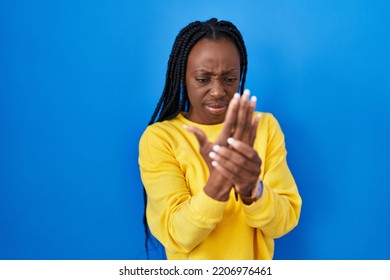 Beautiful Black Woman Standing Over Blue Background Suffering Pain On Hands And Fingers, Arthritis Inflammation 