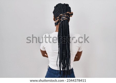 Beautiful black woman standing over isolated background standing backwards looking away with crossed arms 