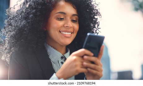 Beautiful Black Woman Using Smartphone, Typing Email Message, Browsing Internet, e-Commerce Online Shopping, Social Media. African American Woman Standing on City Street Using Mobile Phone App - Powered by Shutterstock