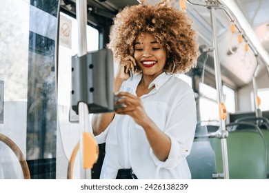 Beautiful black woman using ticket machine and paying contactless for bus or tram. Modern city lifestyle and public transportation concept. - Powered by Shutterstock