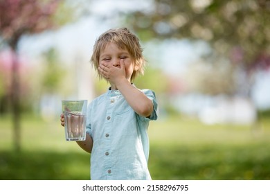 Beautiful blond child, boy, drinking water in the park on a hot summer day - Shutterstock ID 2158296795