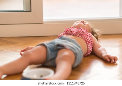 Beautiful Blond Child Crying And Shouting With Tantrum Laying On The Floor At Home.