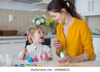 Beautiful blond child, toddler boy, painting easter eggs with mother at home, making easter wreath with rainbow colors - Powered by Shutterstock