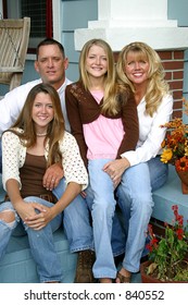 A Beautiful Blond Family Sitting Together On Their Front Porch.