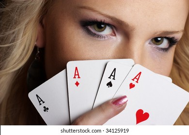 Beautiful blond girl hides behind poker cards