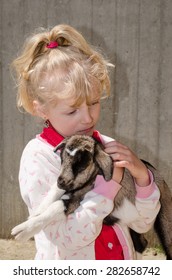 Beautiful Blond Girl Holding Baby Goat