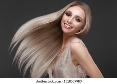 Beautiful blond girl in move with a perfectly smooth hair, and classic make-up. Beauty face. Picture taken in the studio.