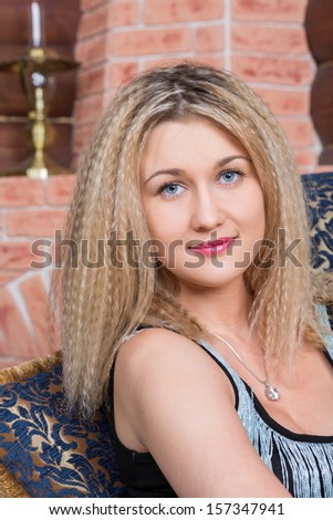 Beautiful blond girl with a pendant around his neck in a cozy house