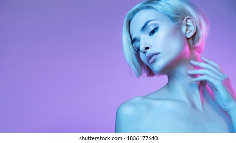 Beautiful  blond girl with  perfect skin on neon lilac background posing aside empty copy space for ad. 