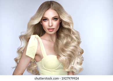 Beautiful blond girl with a perfectly curls hair, and classic make-up. Beauty face and hair. Picture taken in the studio.