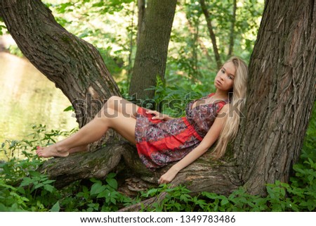 Beautiful blond girl posing for photo in dress at the park