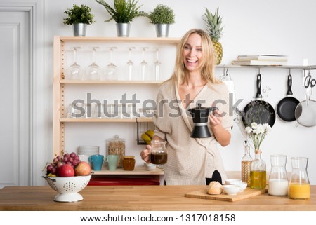 Beautiful blond girl putting coffee in the jug in her small kitchen