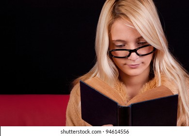 Beautiful Blond Girl Reading A Book With A Dark Background