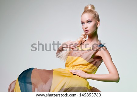 Beautiful blond girl in summer dress looking like Barbie doll