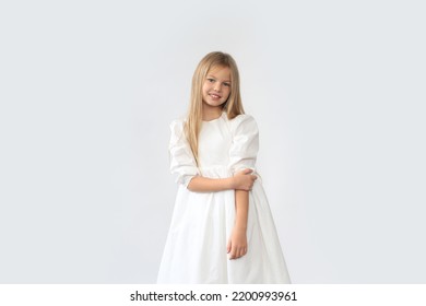 Beautiful blond girl in a white dress is standing on a white background