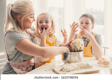 Beautiful blond mom teaching her two children cooking on the kitchen. Parent making everyday breakfast together with kids. Family at home lifestyle photo. - Powered by Shutterstock