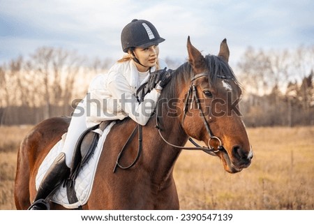 Beautiful blond professional female jockey riding a horse. Friendship with horse. High quality photo