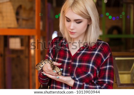 A beautiful blond woman is holding a small royal python in her hands. Contact zoo.
