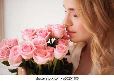 Beautiful blond woman holds pink roses