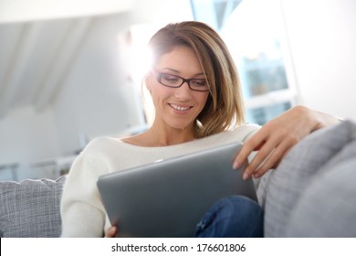 Beautiful blond woman at home websurfing on internet - Powered by Shutterstock