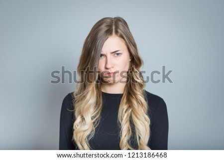 beautiful blond woman is offended, isolated over gray background