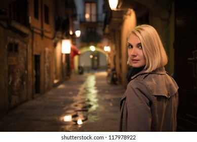 Beautiful Blond Woman In Raincoat Walking Alone Outdoors At Night