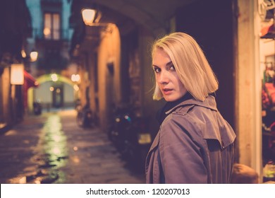 Beautiful Blond Woman In Raincoat Walking Alone Outdoors At Night