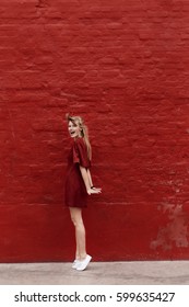 Beautiful Blond Woman In Red Against Red Wall, Portrait