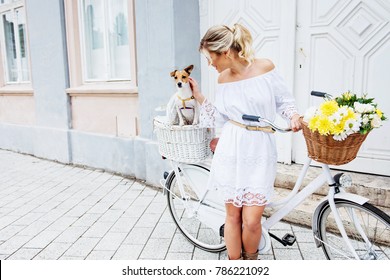 Beautiful, blond woman riding a bicycle in a town with her dog  - Powered by Shutterstock