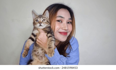 Beautiful blonde Asian woman very happy holding adorable cat. Woman hugging cute cat isolated on white background. Adorable domestic pet concept. - Powered by Shutterstock