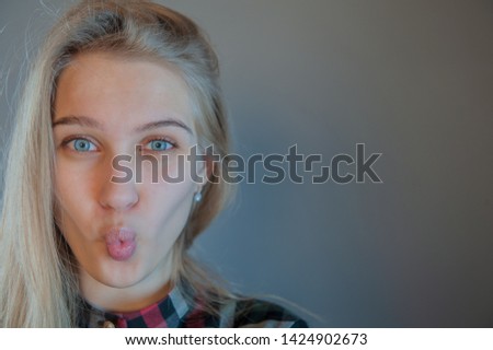 beautiful blonde with blue eyes in plaid dress touches her hair. Young actress shows acting exercises. woman actively expresses her emotions and poses for camera