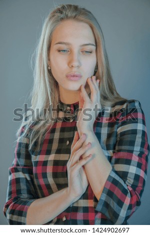 beautiful blonde with blue eyes in plaid dress touches her hair. Young actress shows acting exercises. woman actively expresses her emotions and poses for camera