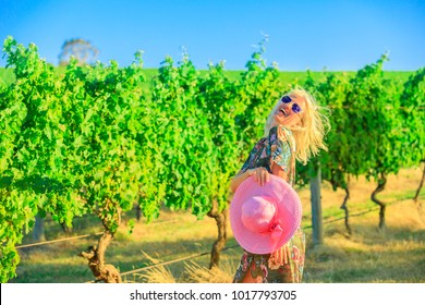 Beautiful Blonde Carefree Woman With Hat Walks Near The Vineyards. Happy Woman Enjoying During A Popular Wine Tasting Tour In The Wine Region Of Margaret River, Western Australia.