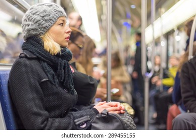Beautiful blonde caucasian lady, wearing winter coat, traveling by metro in rush hour. Public transport.