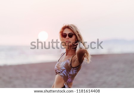 Beautiful blonde Caucasian woman wearing swimsuit and posing on beach.