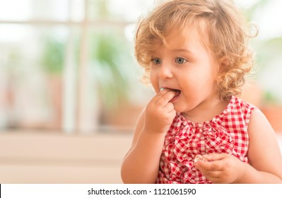 Schönes blondes Kind mit blauen Augen, das zu Hause Süßigkeiten isst.