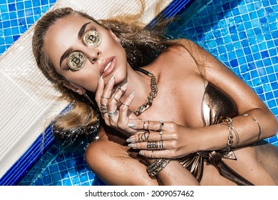 Beautiful blonde girl with bitcoin coins. Bitcoin cryptocurrency. Sexy bikini woman in pool with bitcoin. Luxury lifestyle.