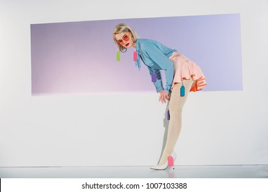 Beautiful Blonde Girl With Colorful Blank Tags On Clothes Stepping Through Aperture On Grey