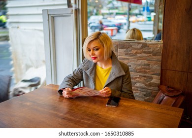 Beautiful Blonde Girl In A Fast Food Cafe Reading The Menu