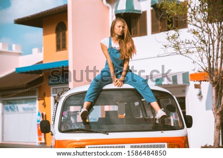 Beautiful blonde girl in modern fashion on a background of palm trees, a hippie car. Dissolute girl with happy emotions.