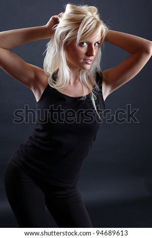 A beautiful blonde girl posing in a studio wearing a black undershirt.