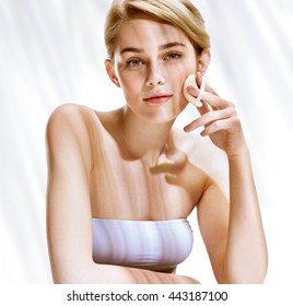 Beautiful blonde girl removing make up from her face. Youth and skin care concept