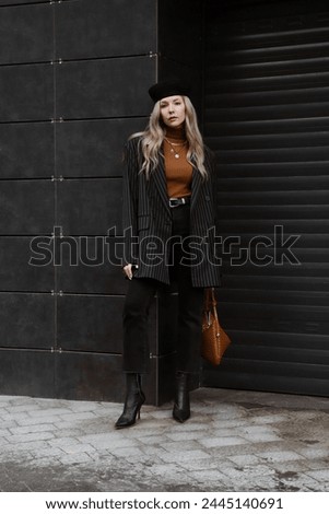 beautiful blonde girl with wavy hair dressed in black oversized jacket, pants, heels, beret, brown sweater and bag, accessories, stylish fashion outfit, full length lifestyle model
