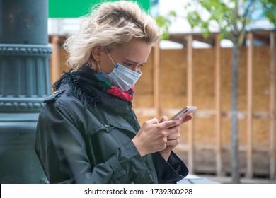 Beautiful Blonde Girl Or Woman With Mask Checking The App Stop Covid On The Smartphone In The Street During Covid Or Coronavirus Emergency, Tracing App, Tracking System, Masks Mandatory Or Compulsory